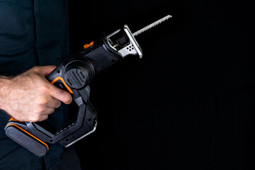 Cordless saw in hand on black background