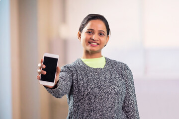 Wall Mural - Cheerful young adult indian woman showing modern smartphone