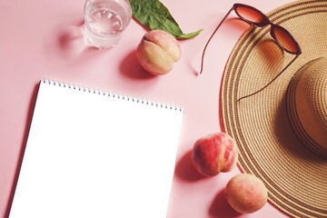 Wall Mural - Summer lifestyle photo. White sheet of paper, juicy peaches, straw hat, sunglasses and a glass of water on a pink background. Holiday, travel concept