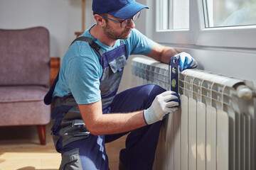 Wall Mural - Central heating mechanic and handyman fixing home radiator, gas crisis and seasonal issues.