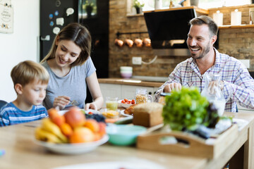 Wall Mural -  Young happy family enjoying in their breakfast time in dining room