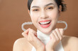© tonefotografia - A young woman with beautiful teeth is holding Invisalign, healthy dental concept