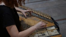A Woman With Red Hair Is A Street Musician Playing A Melody On A Classic Shchik Stringed Instrument.