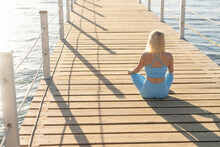 Woman Exercising On Pontoon By The Sea