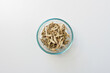 High angle closeup of dried marshmallow root in glass dish on white background (selective focus)