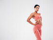 © halayalex - Tanned fitness woman in pink sports clothing. Sexy young beautiful model with perfect body.Female isolated on grey background in studio. Stretching out before training