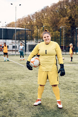 Wall Mural - Happy soccer goalie with ball during sports training at stadium looking at camera.