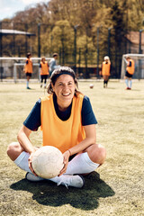 Wall Mural - Happy athletic woman has a break during soccer training on playing field.