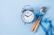 Time to lose weight , intermittent fasting eating control or time to diet concept , alarm clock with spoon  decoration on a blue background