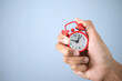 © Cozine - Alarm clock in hand on a blue background , time management  or working hour of everyday life concept