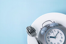 Time To Lose Weight , Intermittent Fasting Eating Control Or Time To Diet Concept , Alarm Clock With Dish And Spoon  Decoration On Blue Background
