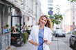 © bisonov - Stylish beautiful business woman in a white jacket on the street
