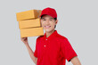 Young asian man in uniform red and cap standing carrying box stack isolated white background, employee holding cargo or package, courier and delivery, transportation and service, logistic and cargo.