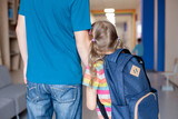 Fototapeta  - First day at school. Stressed and worried kid and father holding hands. Child girl with backpack in first grade of primary school. Concept of back to school crisis, support, protection, togetherness