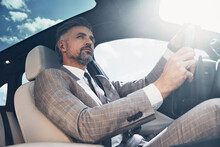 Low Angle View Of Handsome Mature Man In Formalwear Driving A Car