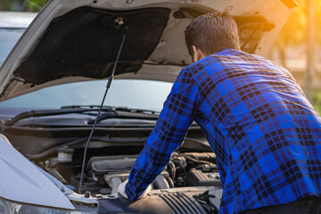 A man's rear view, inspecting or repairing the engine. selective focus maintenance car concept