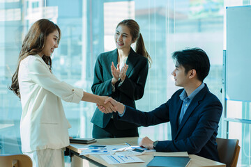 Two successful Asian business partners in elegant outfits join hands for a casual business group teamwork deal. Clap your hands in the modern office. ​​Approved by partners