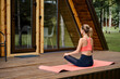 © boomeart - Rear view of woman in the lotus position on the wooden terrace of a country house