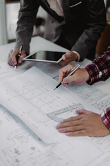 Close up of hands working and brainstorming on paperworks and floor plan drawings about design architectural and engineering for houses and buildings.