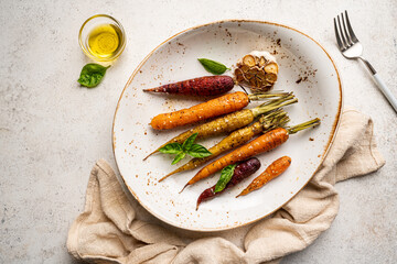 Poster - Roasted young whole colorful carrot with herbs served on plate over white background. Top view