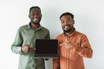 Wall Mural - Two Happy Black Guys Showing Laptop Screen Over White Background