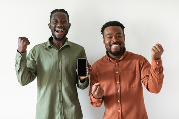 Poster - Two Joyful Black Men Showing Smartphone Screen Over White Background