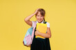 Portrait of a schoolgirl with textbooks and a backpack on a yellow background. Back to school