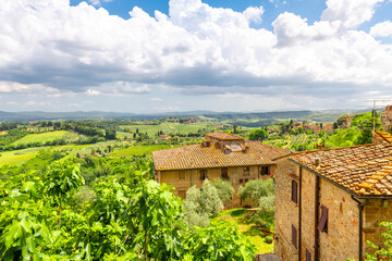 Wall Mural - View of the hills, vineyards and countryside from a terrace above typical Tuscan stone homes in the medieval hill town of San Gimignano, Italy.