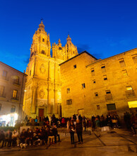 Scenic Salamanca Cityscape At Spring Twilight With Busy Central Square, Illuminated Medieval Building Of Casa De Las Conchas Decorated With Stucco Shells And Baroque Building Of La Clerecia, Spain