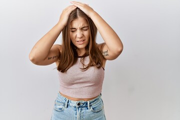 Canvas Print - Young brunette woman standing over isolated background suffering from headache desperate and stressed because pain and migraine. hands on head.