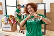 © Krakenimages.com - Middle age woman wearing volunteer t shirt at donations stand smiling in love doing heart symbol shape with hands. romantic concept.