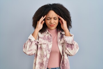 Wall Mural - Young african american woman standing over blue background with hand on head for pain in head because stress. suffering migraine.