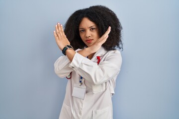 Poster - Young african american woman wearing doctor uniform and stethoscope rejection expression crossing arms doing negative sign, angry face