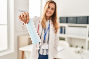 Sticker - Young blonde woman wearing doctor uniform holding medical mask at clinic