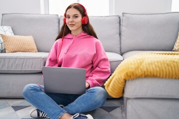 Sticker - Young woman using smartphone and headphones sitting on floor at home