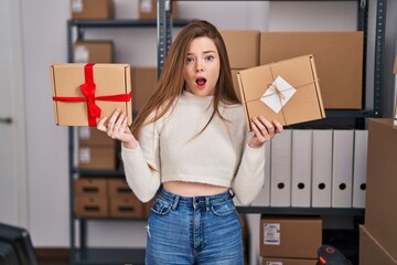 Canvas Print - Young caucasian woman working at small business ecommerce afraid and shocked with surprise and amazed expression, fear and excited face.