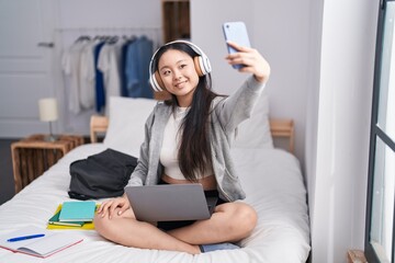 Sticker - Young chinese woman listening to music make selfie by smartphone at bedroom