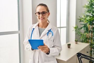 Poster - Young blonde woman wearing doctor uniform using touchpad working at clinic