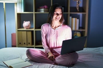 Sticker - Young hispanic woman using computer laptop on the bed smiling looking to the side and staring away thinking.