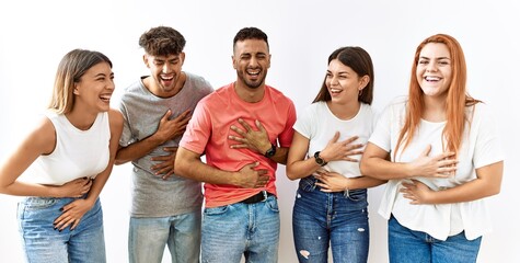 Poster - Group of young friends standing together over isolated background smiling and laughing hard out loud because funny crazy joke with hands on body.