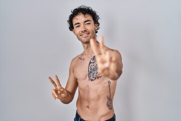 Sticker - Hispanic man standing shirtless smiling looking to the camera showing fingers doing victory sign. number two.