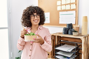 Poster - Young middle east businesswoman smiling happy eating salad at the office.