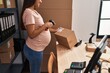 © Krakenimages.com - Young latin woman pregnant business worker scanning package label at office