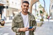 © Krakenimages.com - Young hispanic man smiling confident using smartphone at street