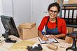 © Krakenimages.com - Young latin woman ecommerce business worker writing on clipboard at office