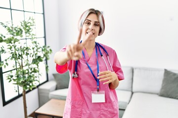 Sticker - Young beautiful woman wearing doctor uniform and stethoscope smiling looking to the camera showing fingers doing victory sign. number two.