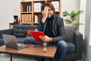 Canvas Print - Handsome middle age man working at consultation office covering one eye with hand, confident smile on face and surprise emotion.