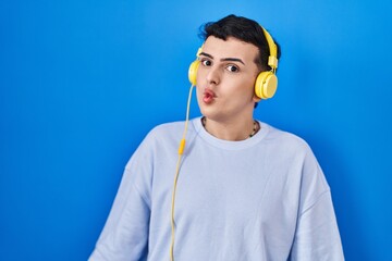 Canvas Print - Non binary person listening to music using headphones making fish face with lips, crazy and comical gesture. funny expression.