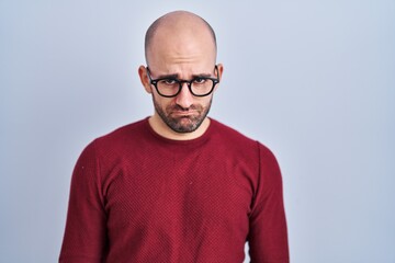 Sticker - Young bald man with beard standing over white background wearing glasses depressed and worry for distress, crying angry and afraid. sad expression.