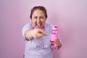 Poster - Senior woman wearing sportswear and headphones pointing displeased and frustrated to the camera, angry and furious with you